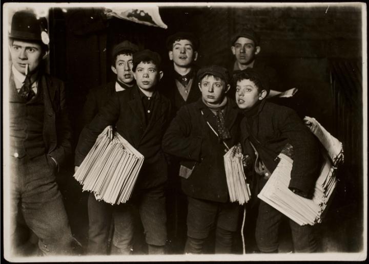 Newspaper boys looking at something off screen. 