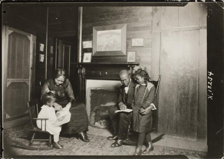 A black family from the 19th century reading together. 
